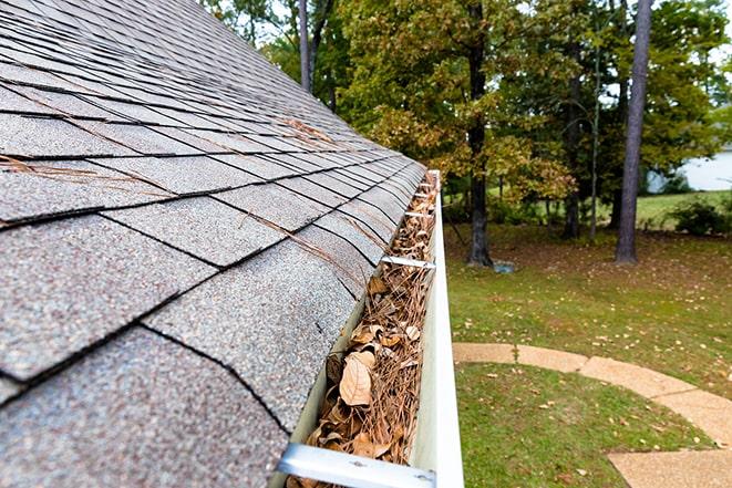 man cleaning gutters on a residential roof